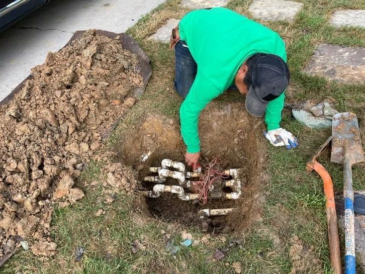 A man in a green shirt is digging a hole in the ground.