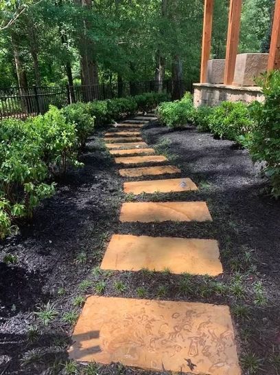 A stone walkway going through a lush green forest.