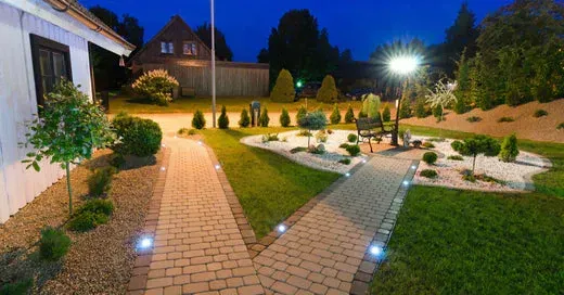 A brick walkway leading to a house at night.