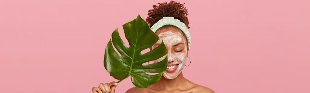 A woman with a mask on her face is holding a leaf in front of her face.