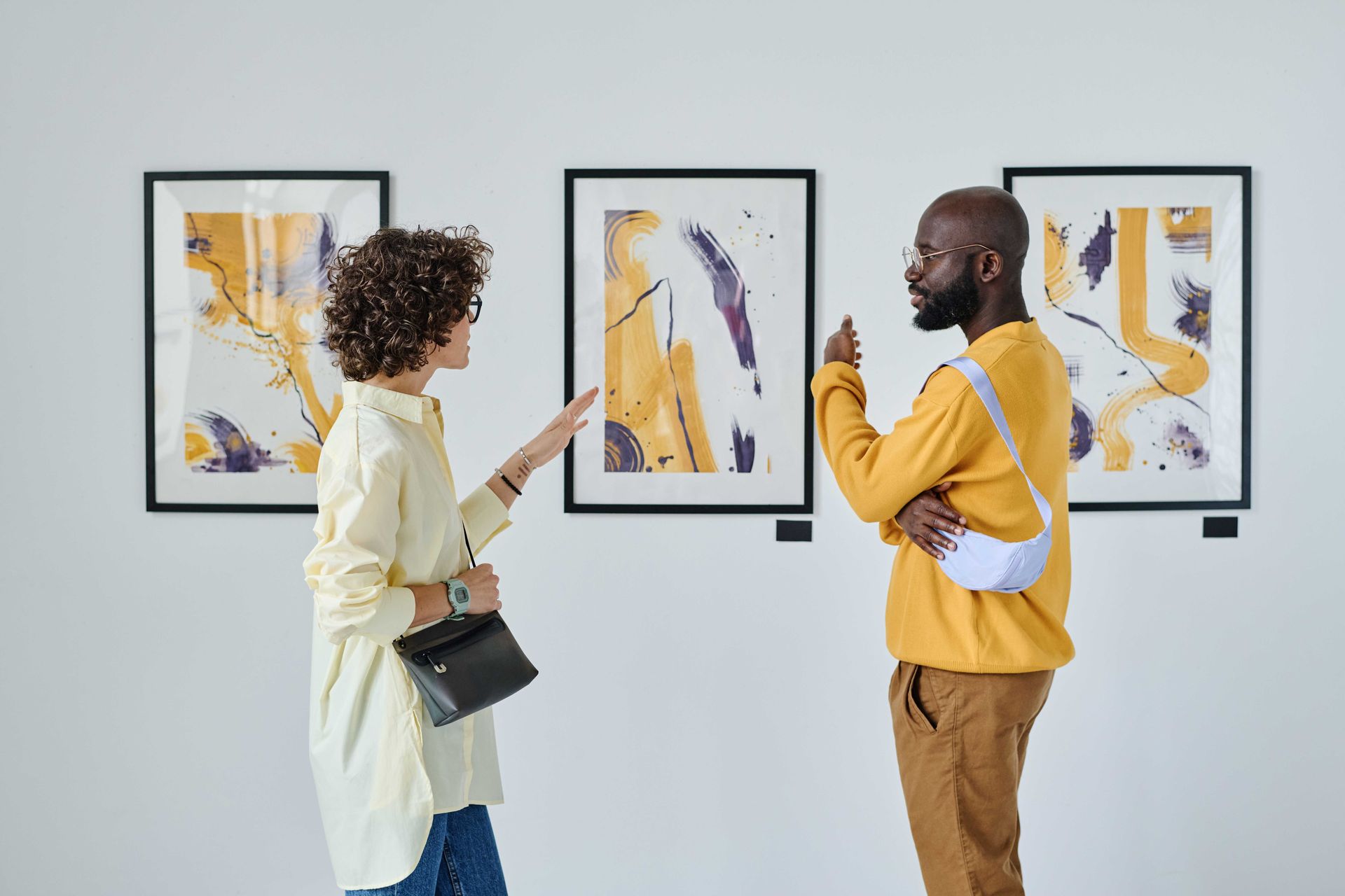 a man and a woman are looking at paintings in an art gallery