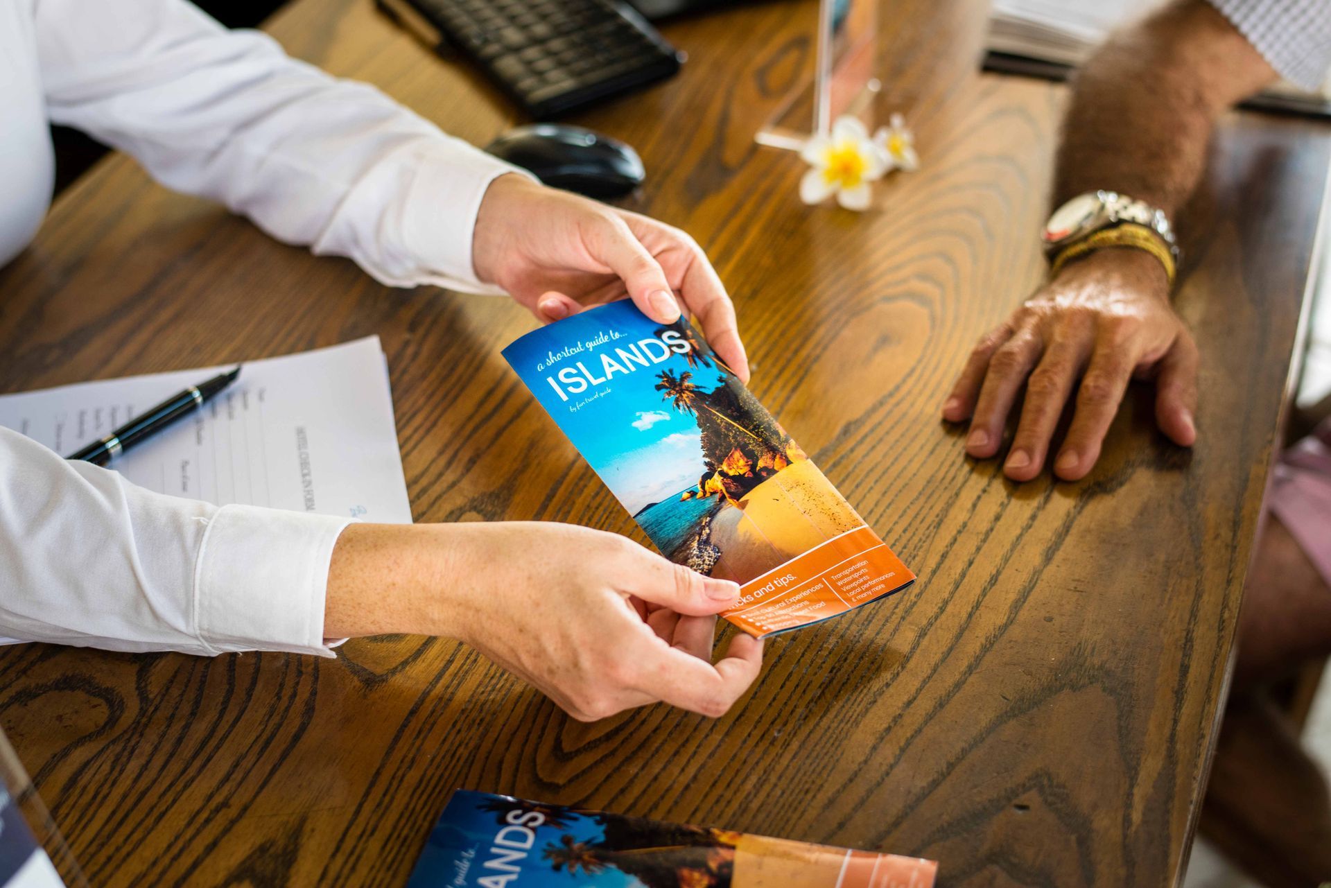 a woman is giving a brochure to a man at a table