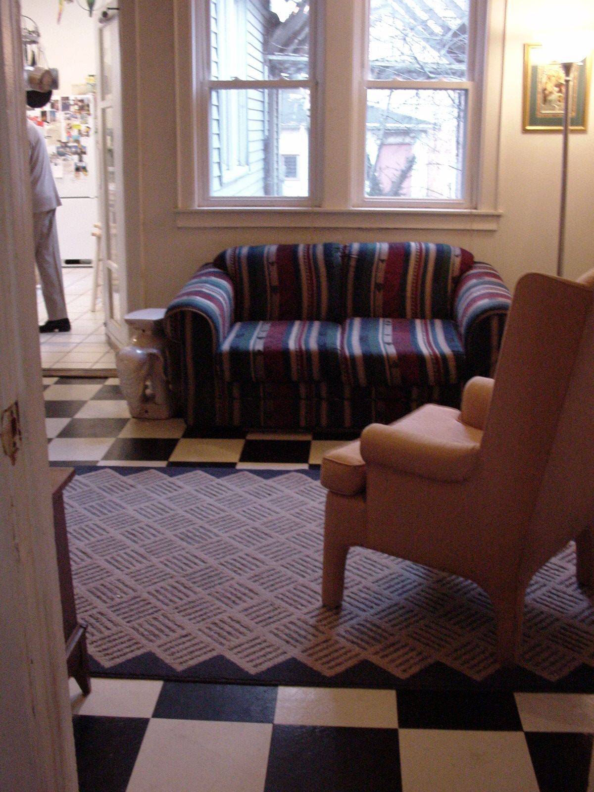 Striped loveseat and tan armchair in a sunlit room with black-and-white tile floor