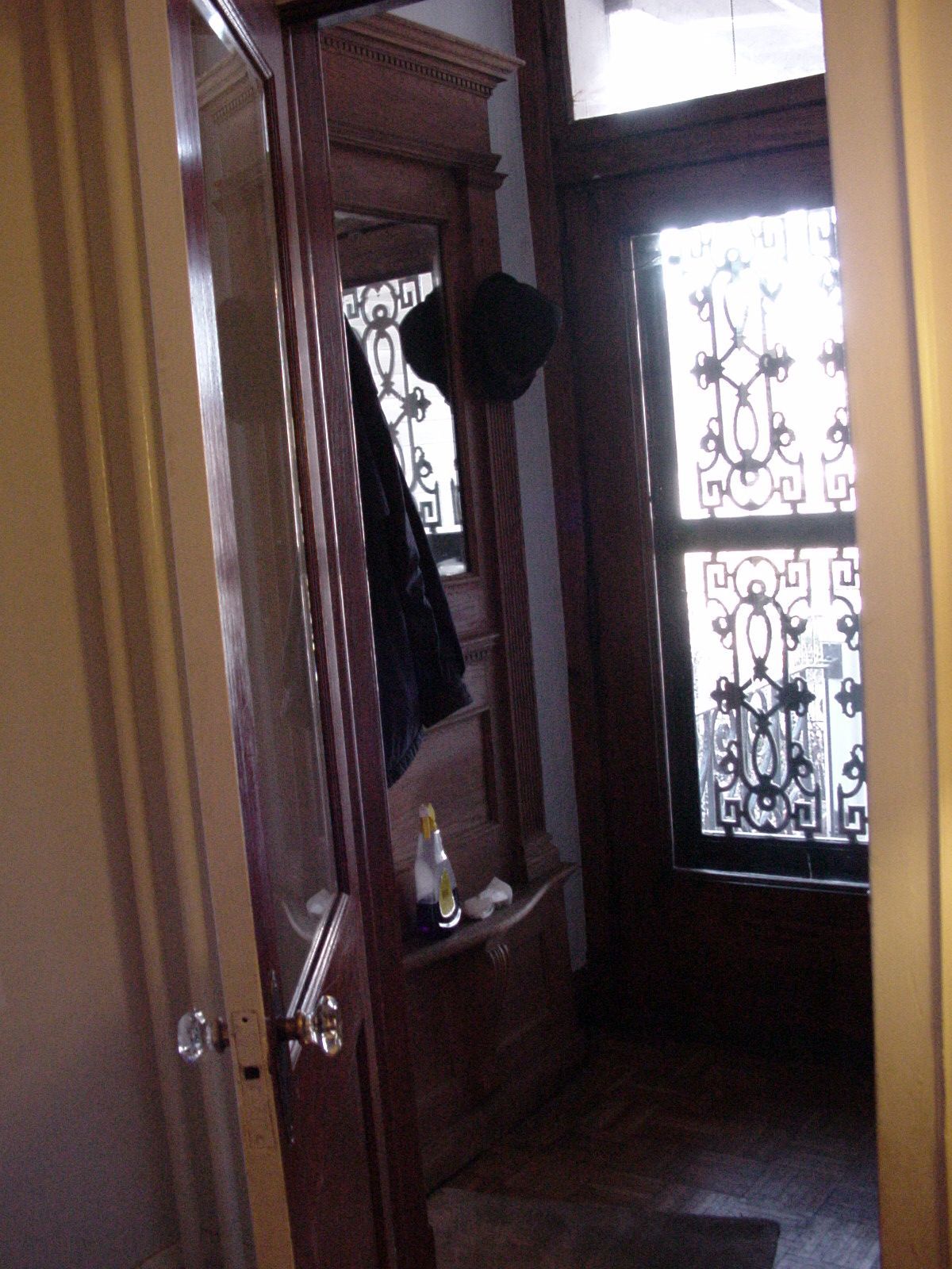Narrow entryway with wood paneling, coat hooks, and a window with ornate frosted glass.