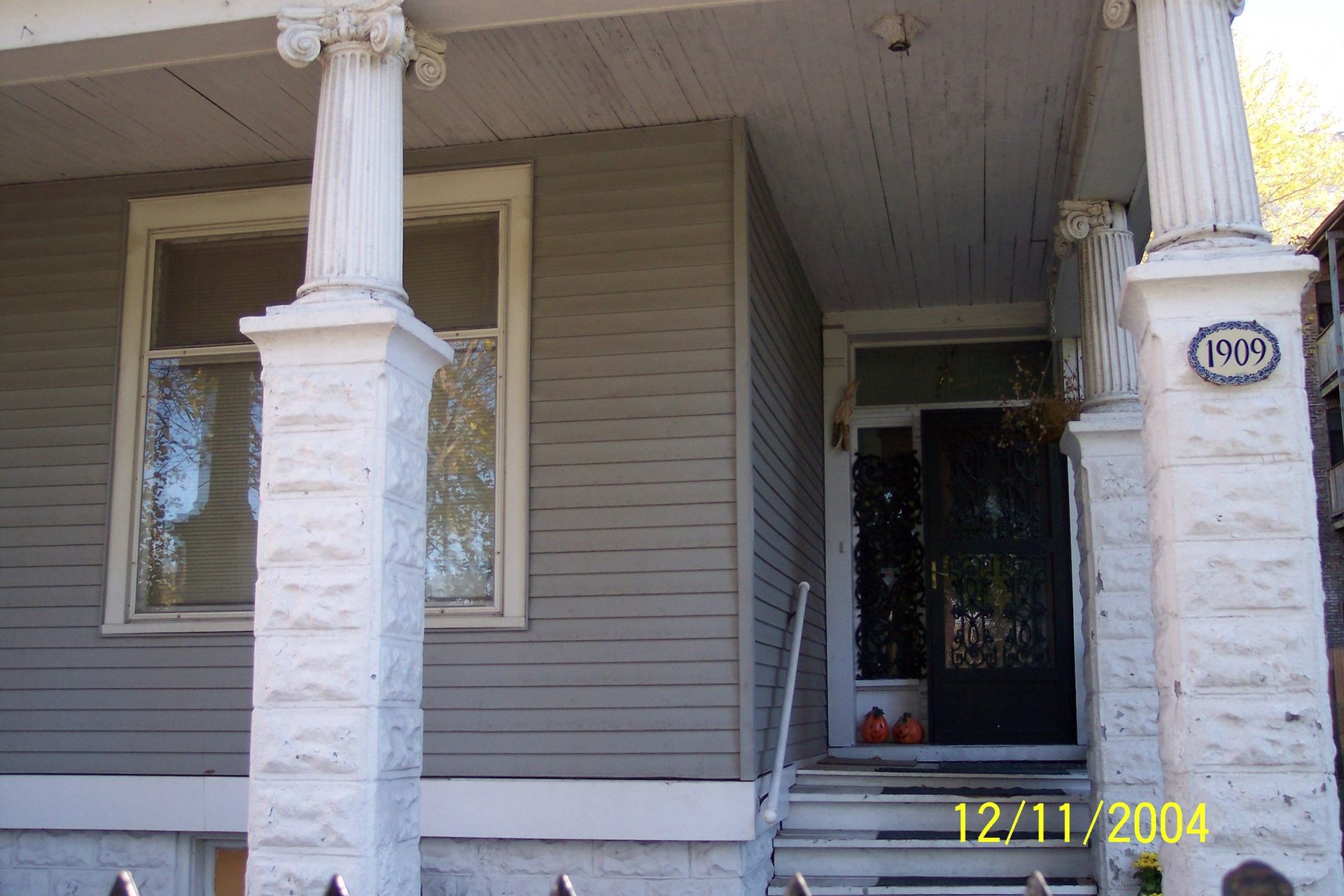 Front porch of a gray house with white columns and a black door, date stamp 12/11/2004.