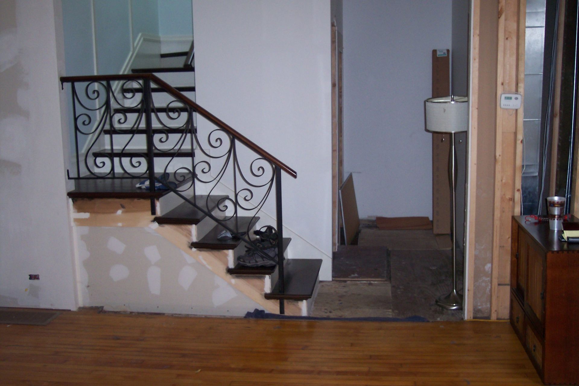 Interior staircase with ornate black railing beside a small landing and hallway