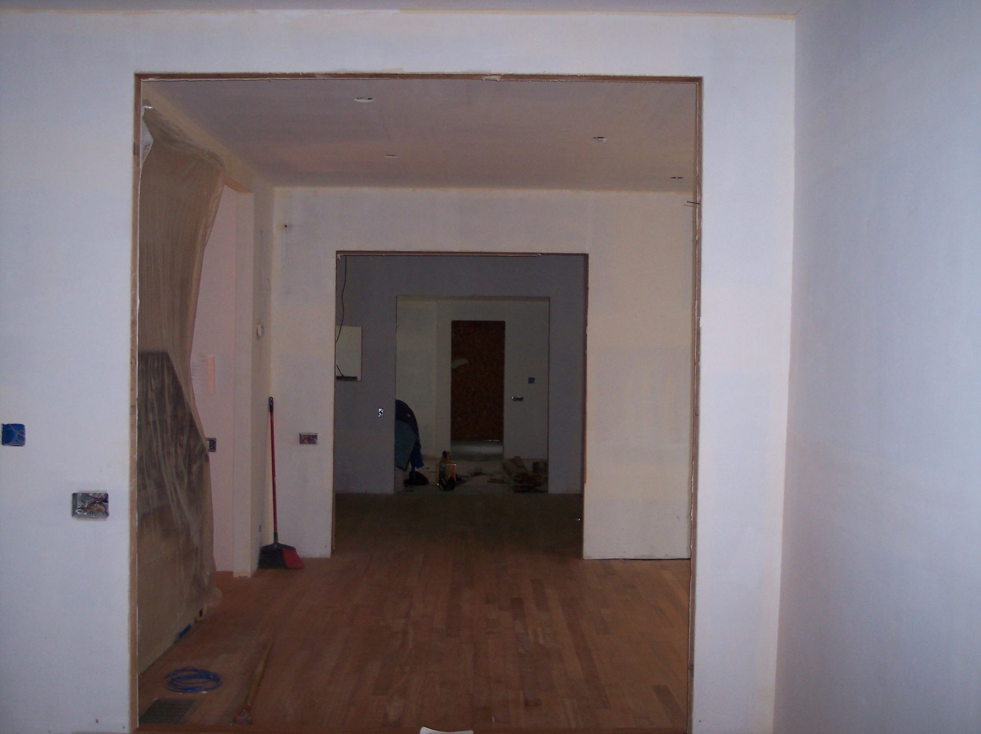 Dim, unfinished interior hallway with wooden floor and doorways