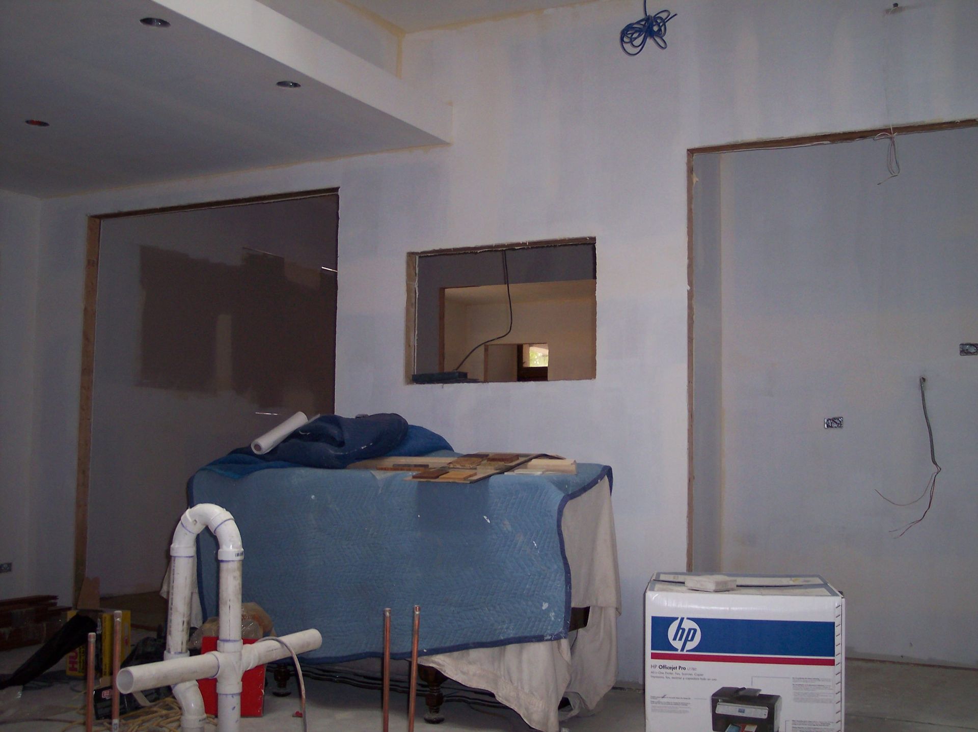 Partially renovated room with covered furniture, an open doorway, and construction materials scattered around.