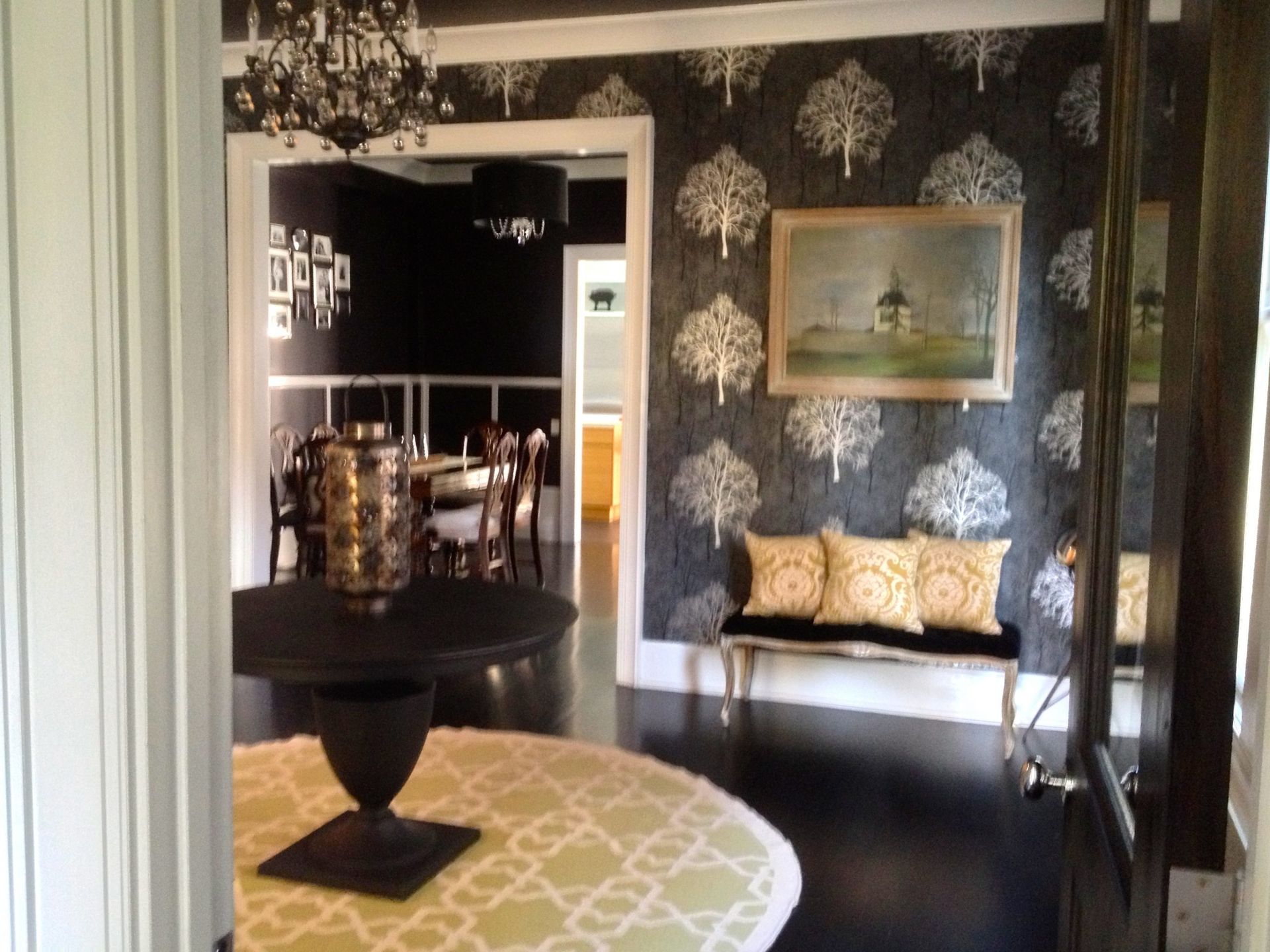 Elegant black-and-gold dining room with chandelier, patterned wallpaper, bench seating, and round table