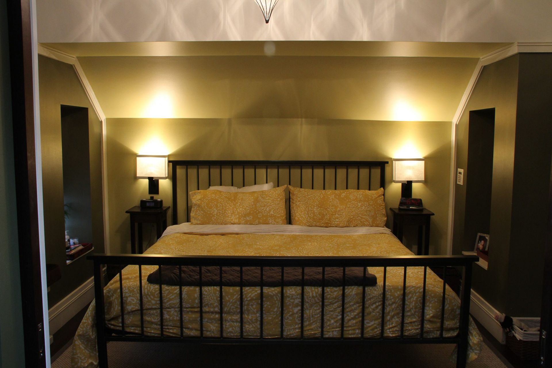 Cozy bedroom with black metal bed frame, cream bedding, and warm bedside lamps