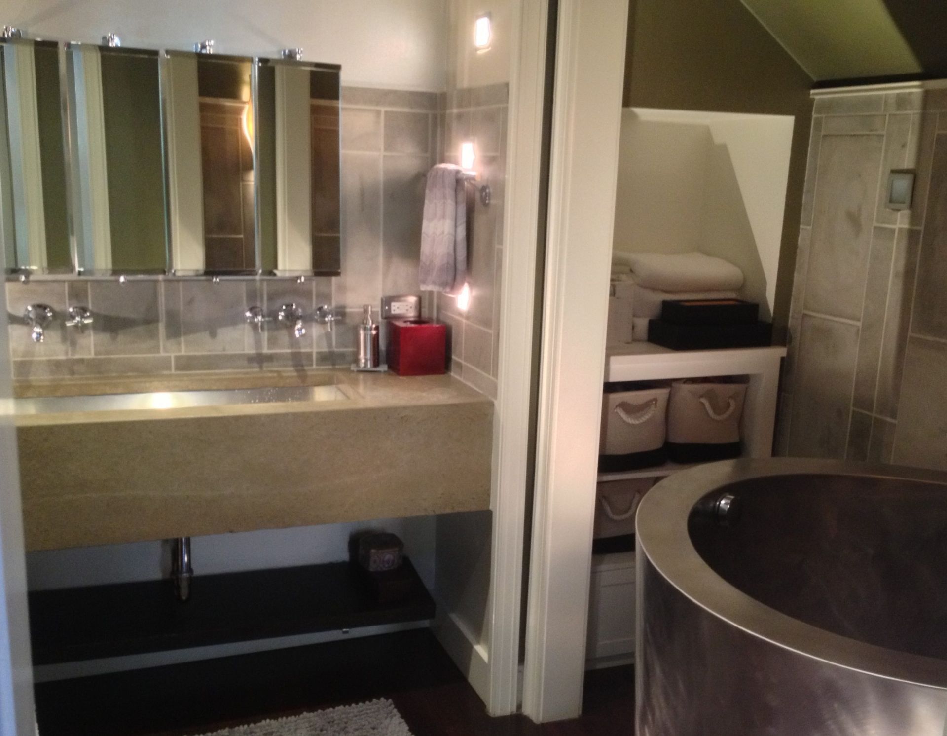 Modern bathroom vanity with mirrors, sink, and a large round tub beside a small adjoining bedroom area