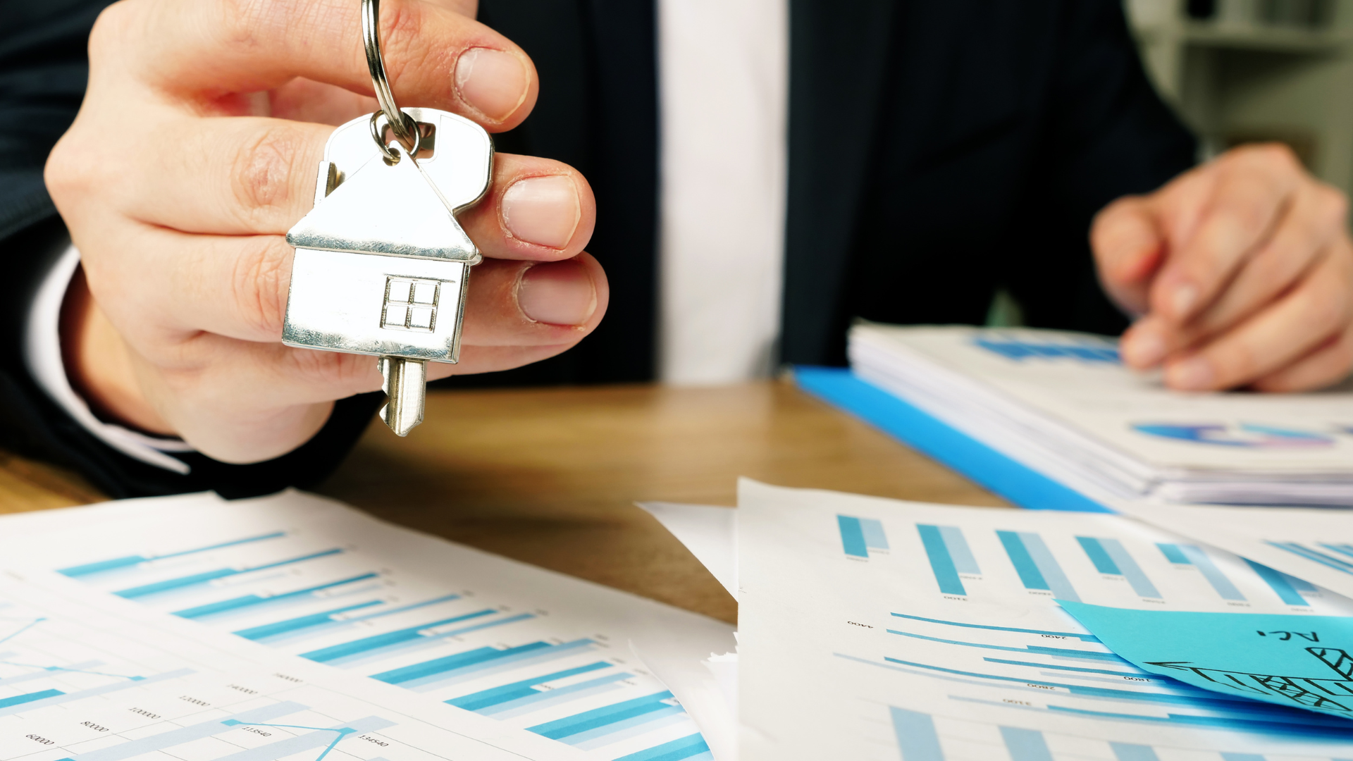 Two red and white dirt bikes parked in a grassy field with red rock desert mountains in the background under a blue sky.