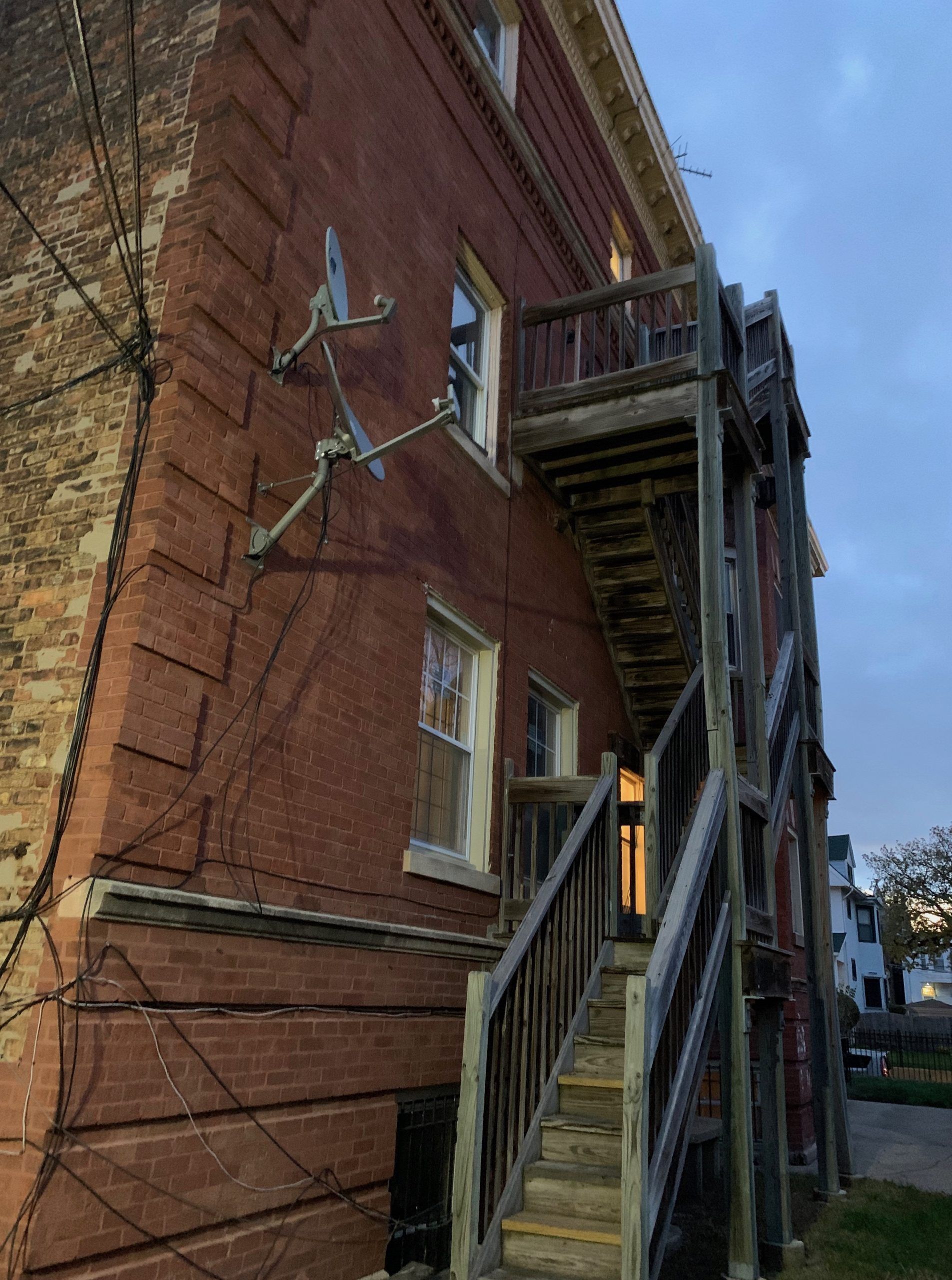 Brick building exterior with wooden stairway and metal balcony on the side.