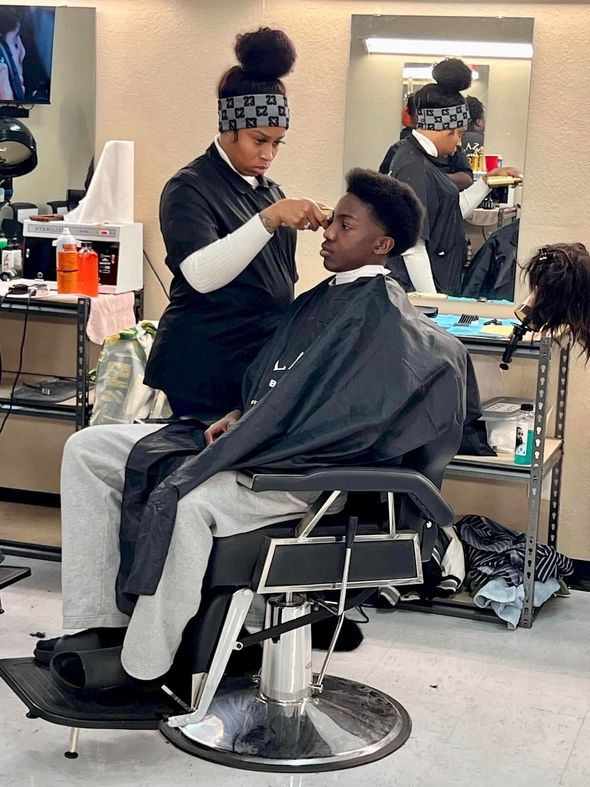 A woman is cutting a man 's hair in a barber shop.