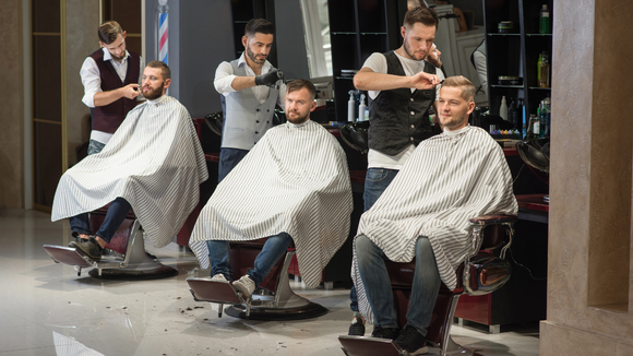 A group of men are getting their hair cut at a barber shop.