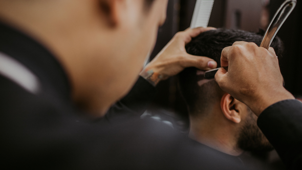 A man is getting his hair cut by a barber.