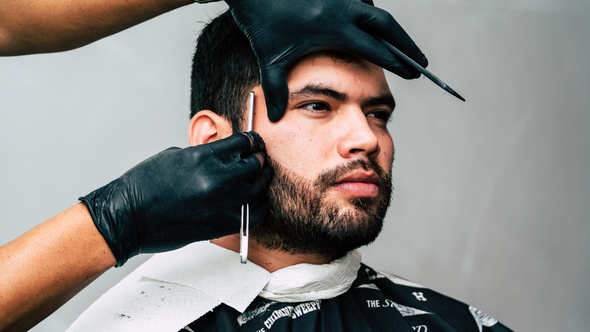 A man is getting his hair cut by a barber.