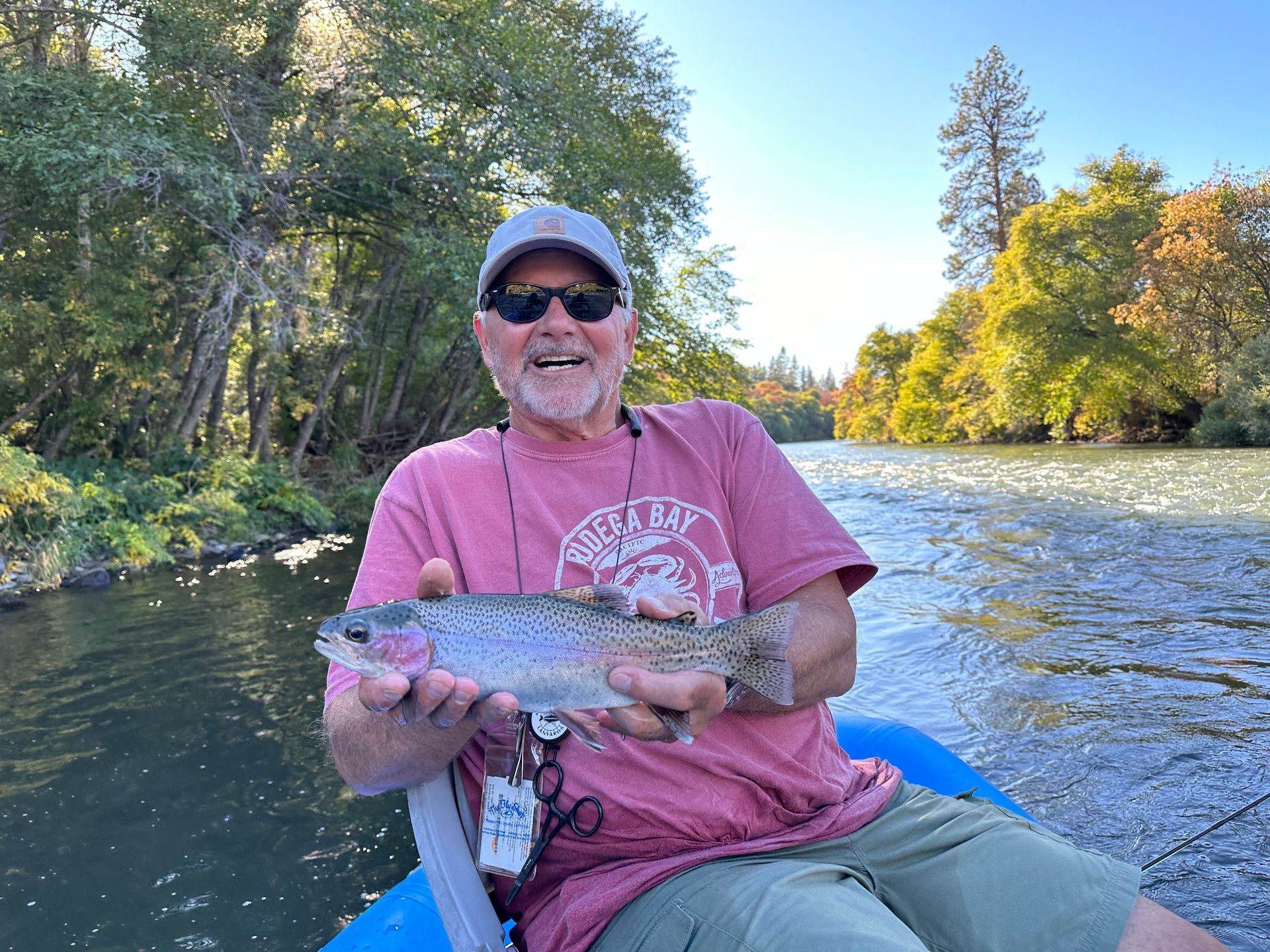 Two men holding a fish in front of a river