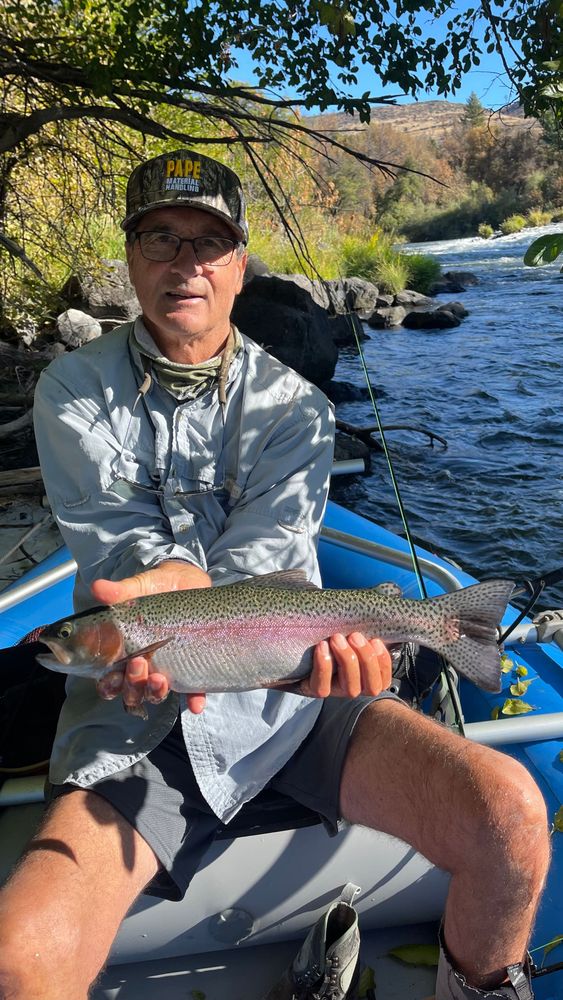 A man is holding a fish in front of a river.