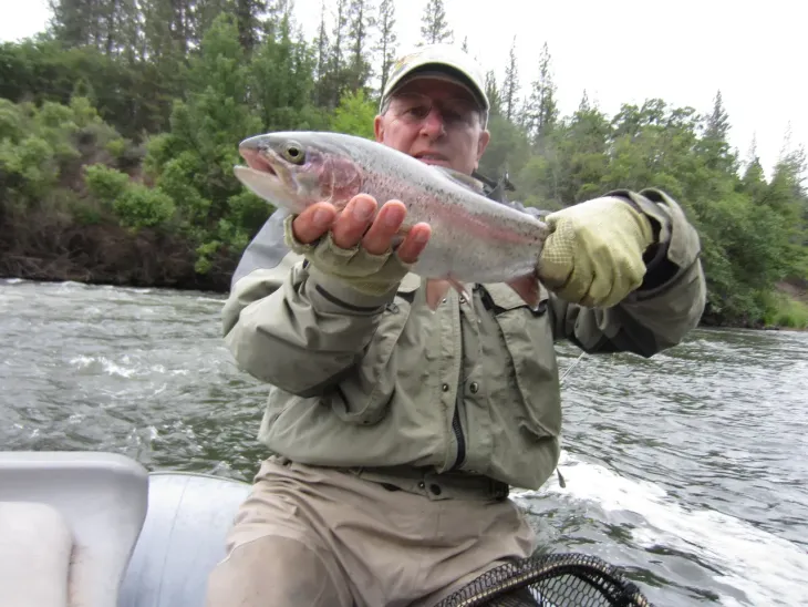 A man in a boat is holding a fish in his hands