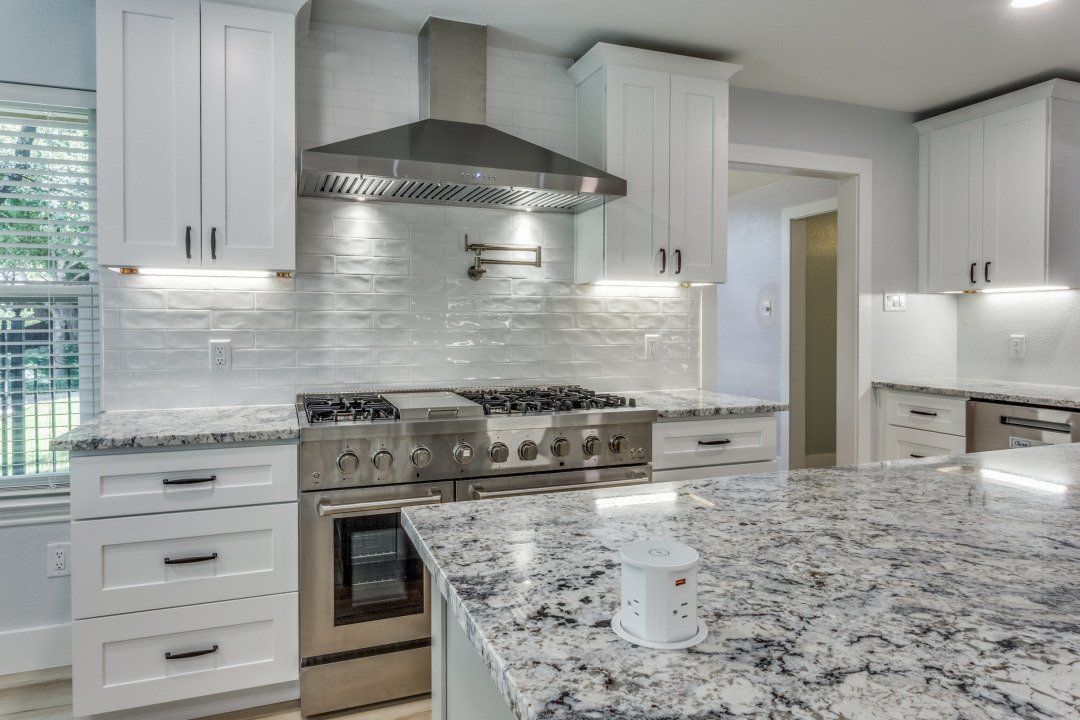 Modern kitchen with white cabinets, stainless steel appliances, and granite countertops.
