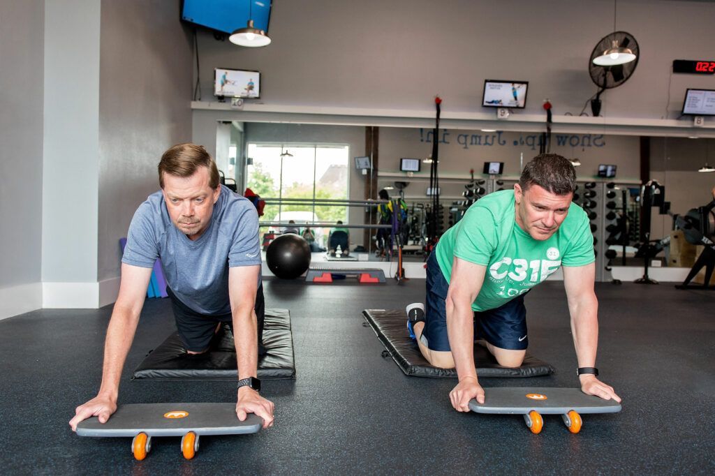 Two men exercising on balance boards in a gym.