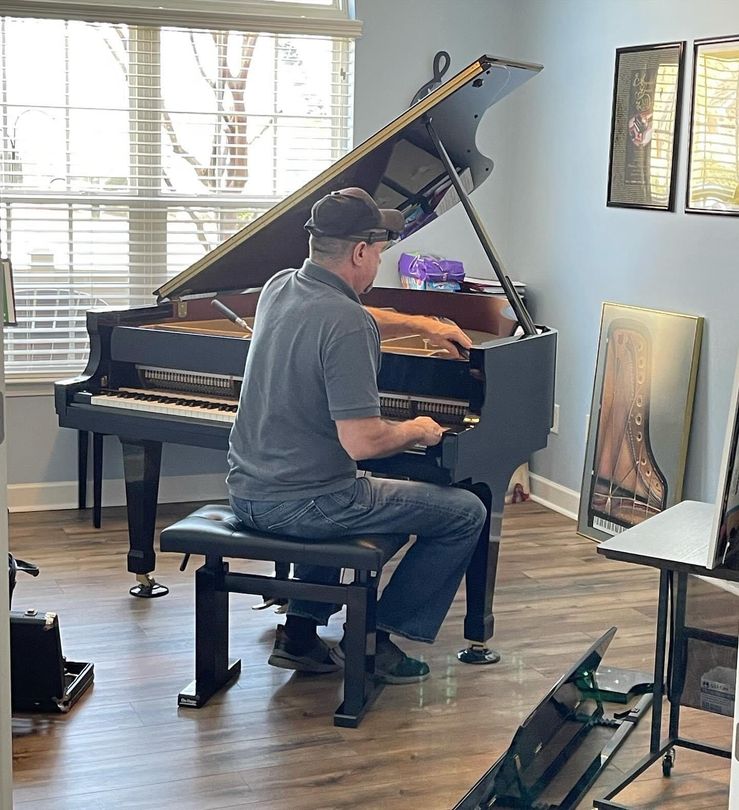 a man is working on a piano with a screwdriver