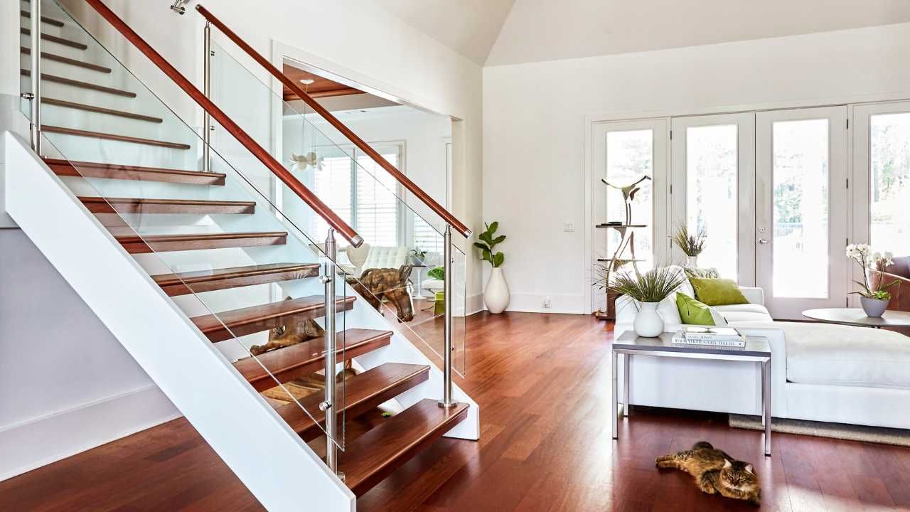 A contemporary living room featuring a glass railing and elegant wooden stairs.