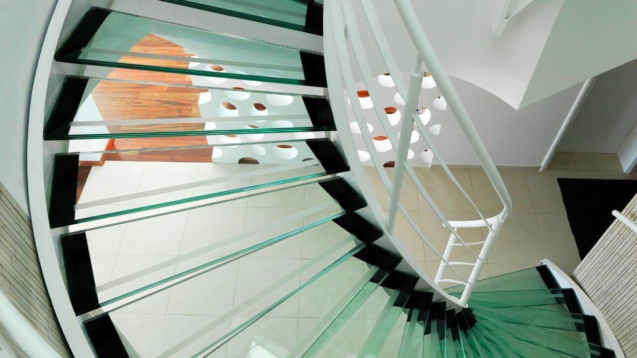 A modern spiral staircase with a sleek glass railing.