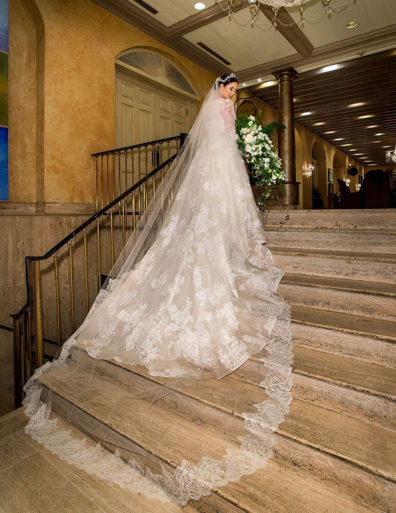 A bride in a long wedding dress is standing on a set of stairs.