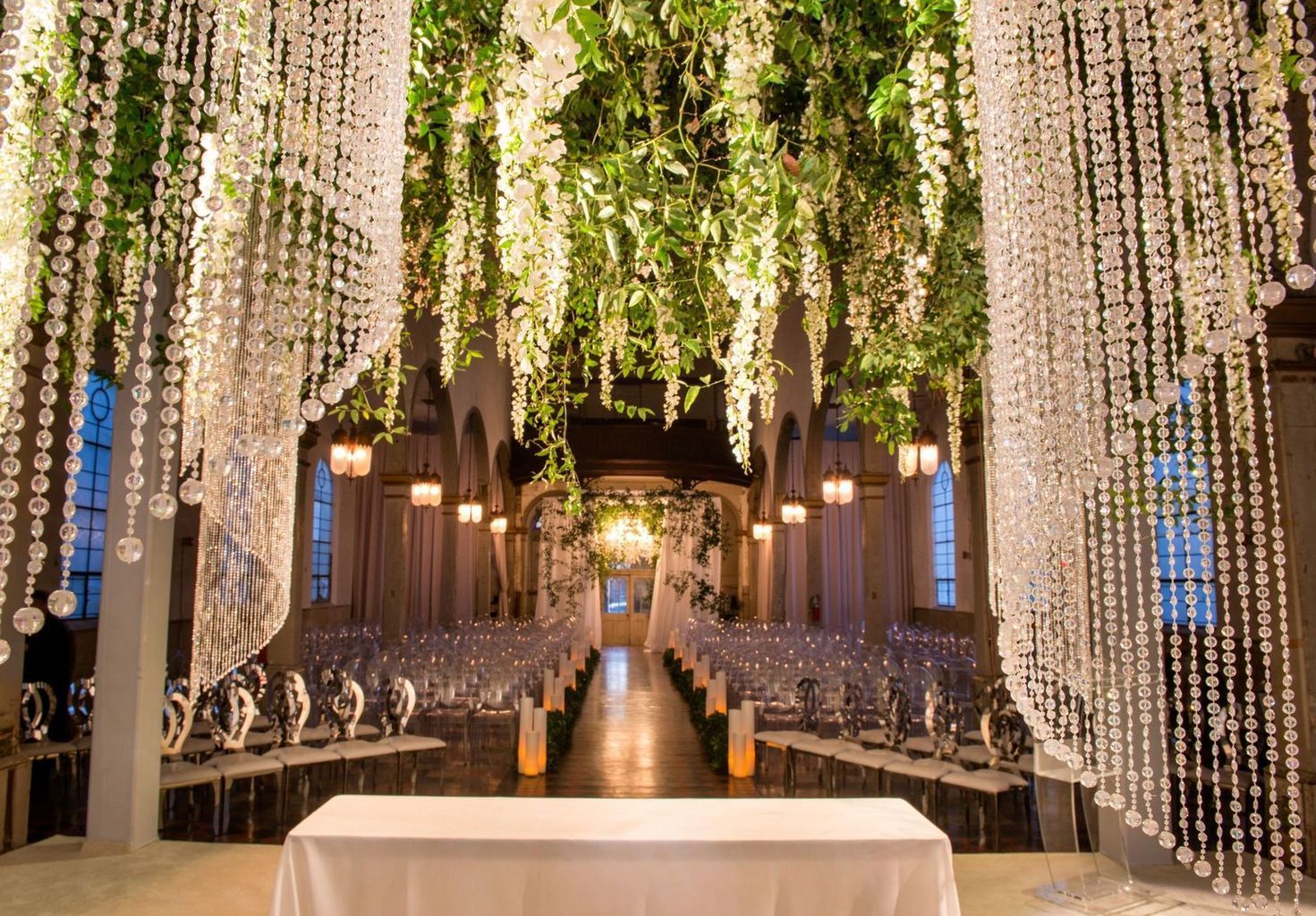 A wedding ceremony is taking place in a church with flowers hanging from the ceiling.