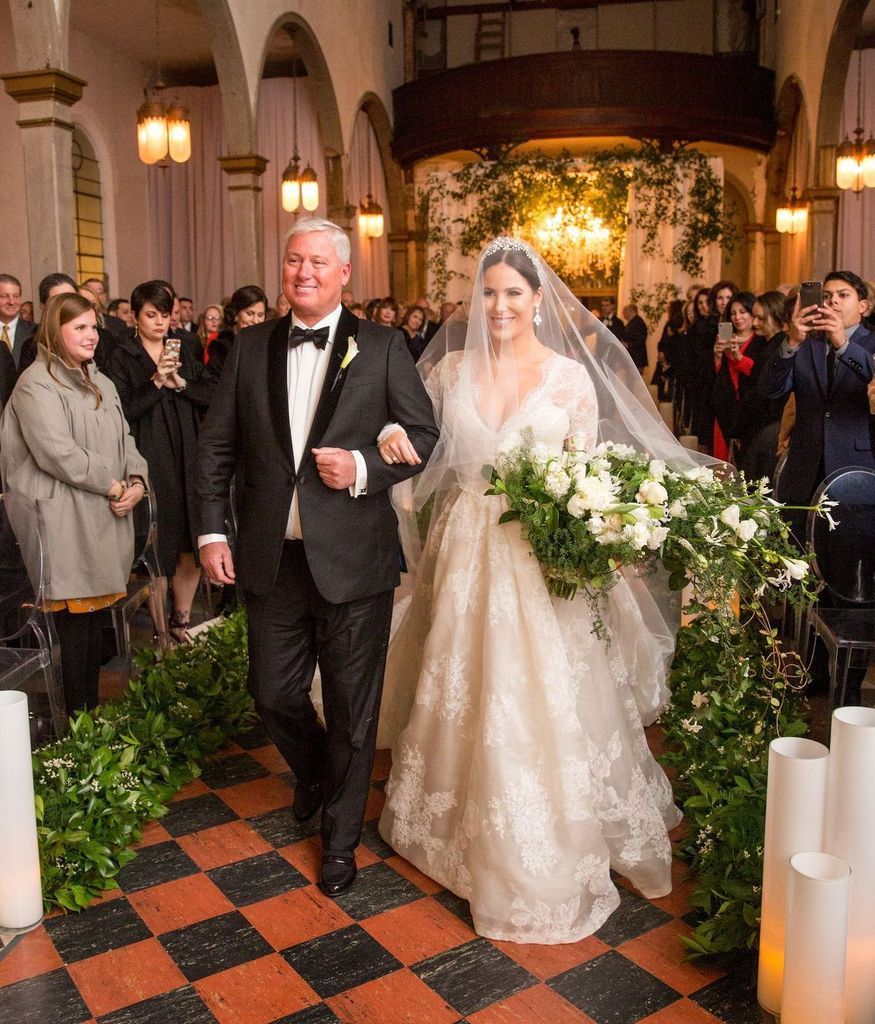 A bride and her father are walking down the aisle of a church.