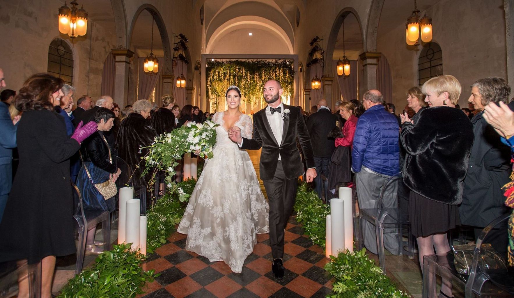 A bride and groom are walking down the aisle of a church.