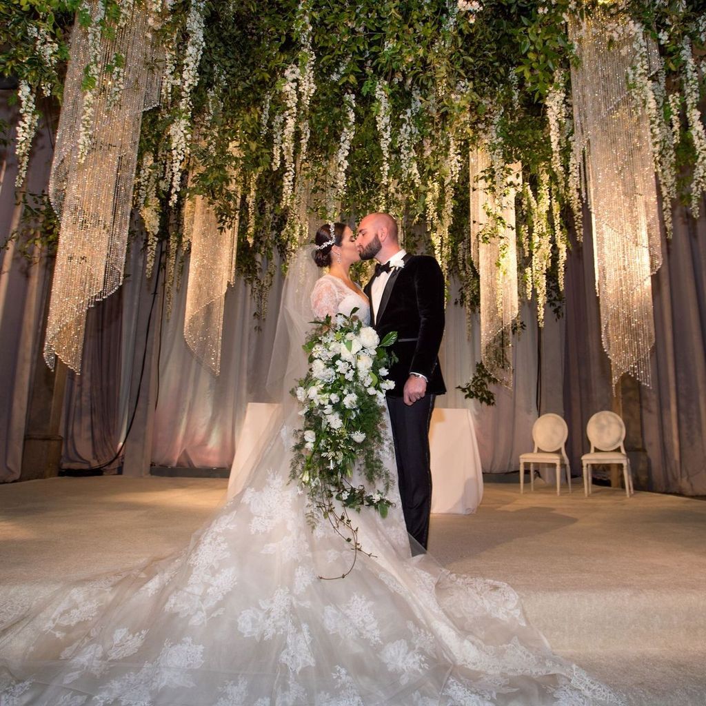 A bride and groom kissing under a canopy of flowers