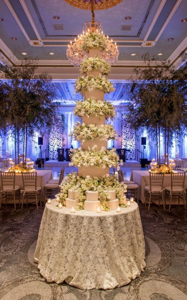 A large wedding cake is sitting on a table in a room with tables and chairs.