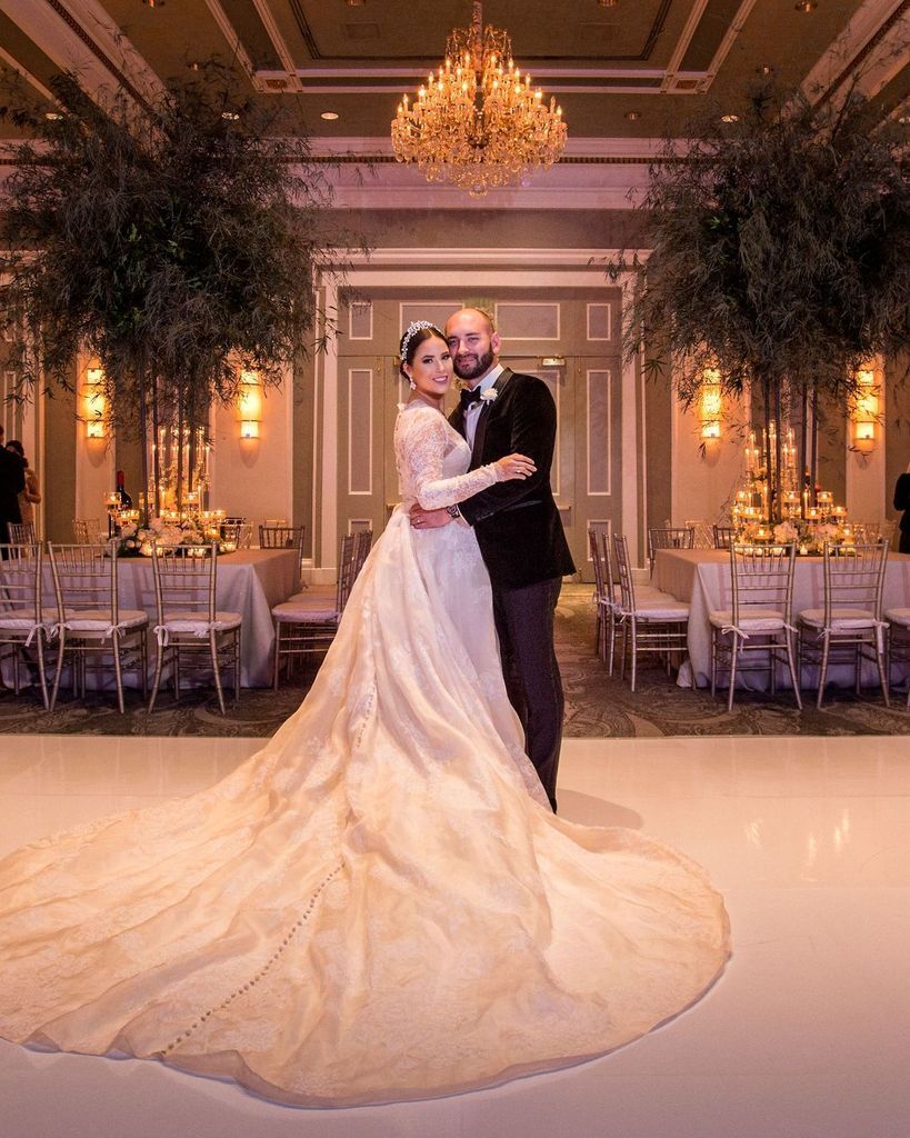 A bride and groom are dancing in a ballroom at their wedding reception.