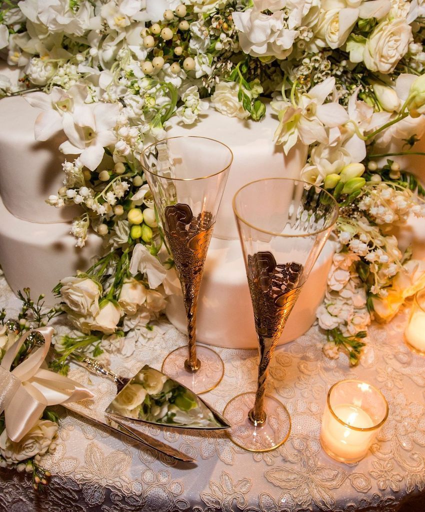Two champagne flutes are sitting on a table next to a wedding cake.