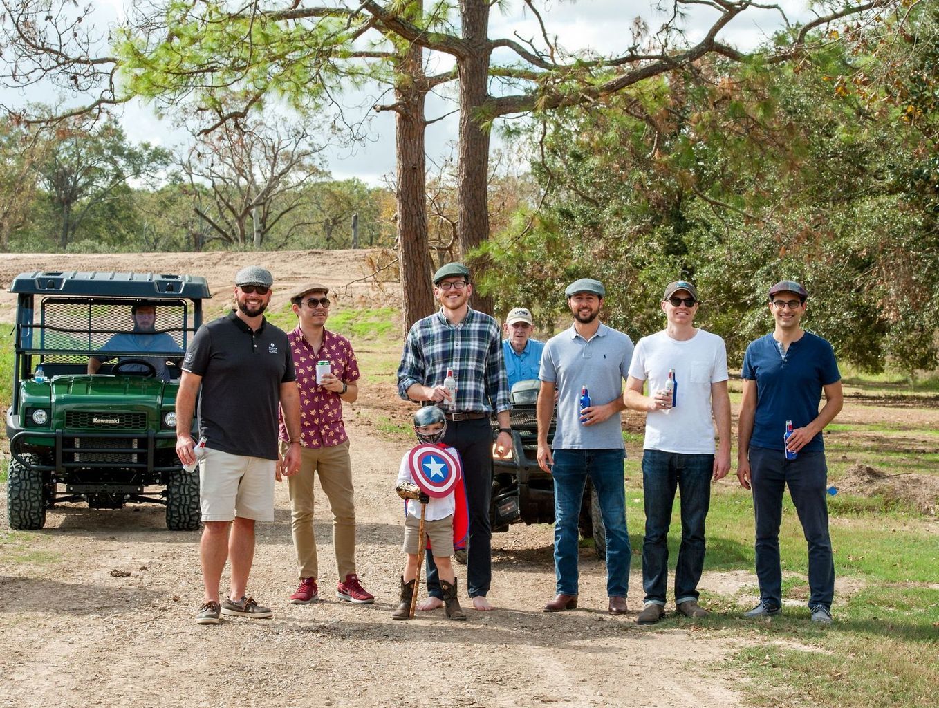 A group of men standing next to each other in front of a golf cart.