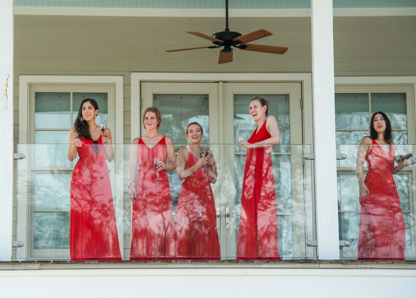 A group of women in red dresses are standing on a balcony.