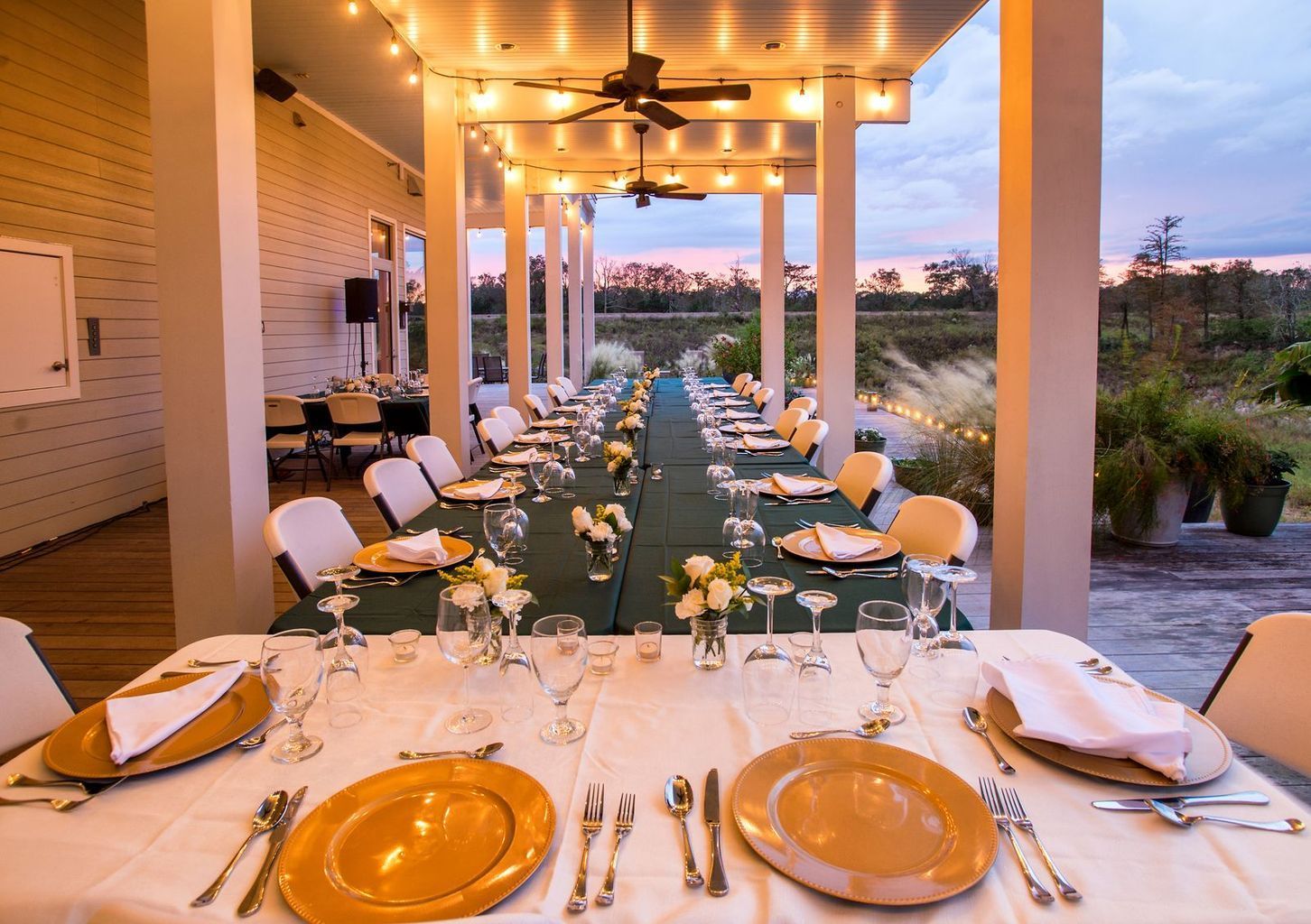 A long table with plates , utensils , and wine glasses on it.