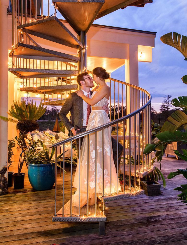 A bride and groom are standing on a spiral staircase.