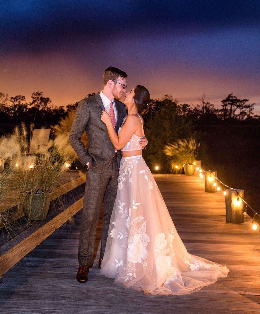 A bride and groom are kissing on a wooden bridge at night.
