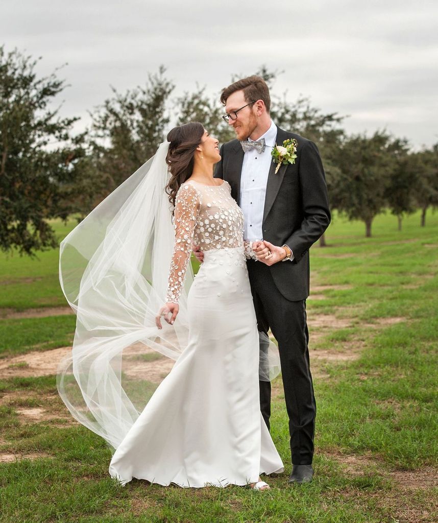 A bride and groom are posing for a picture in a field.