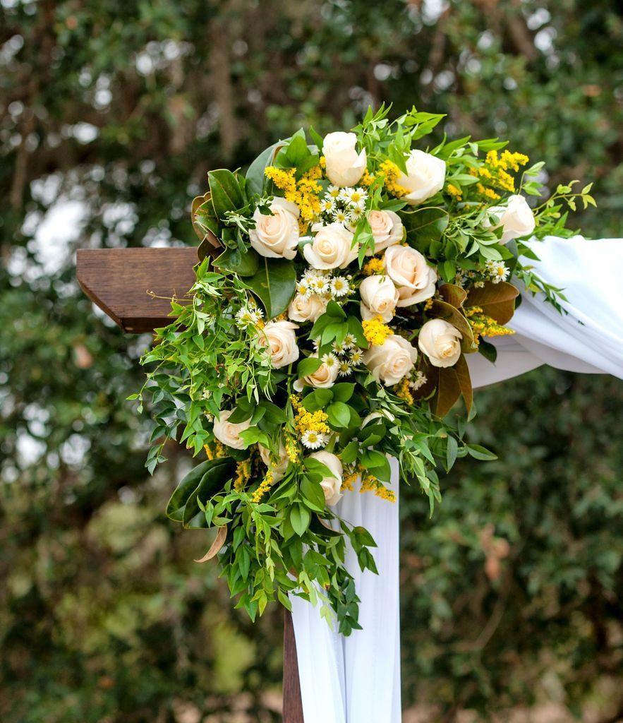 A wooden arch decorated with flowers and greenery for a wedding ceremony.
