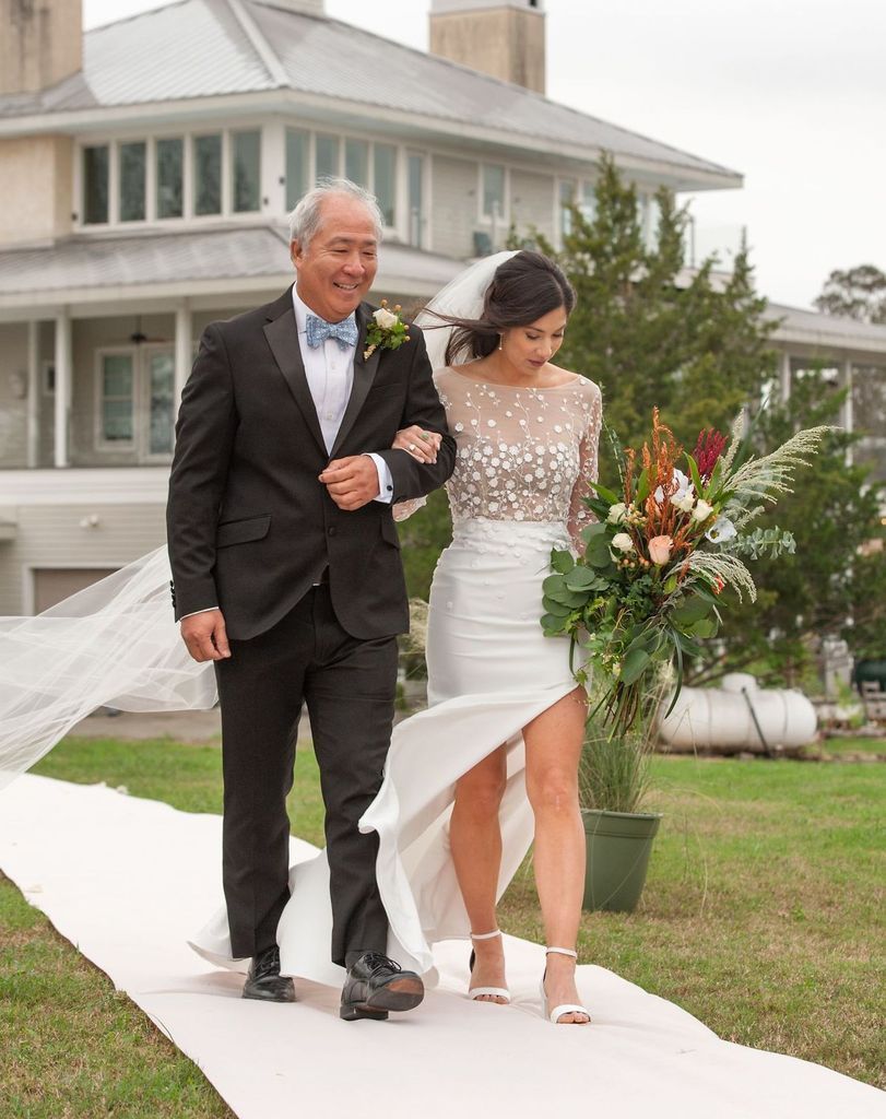 A bride and her father are walking down the aisle at their wedding.