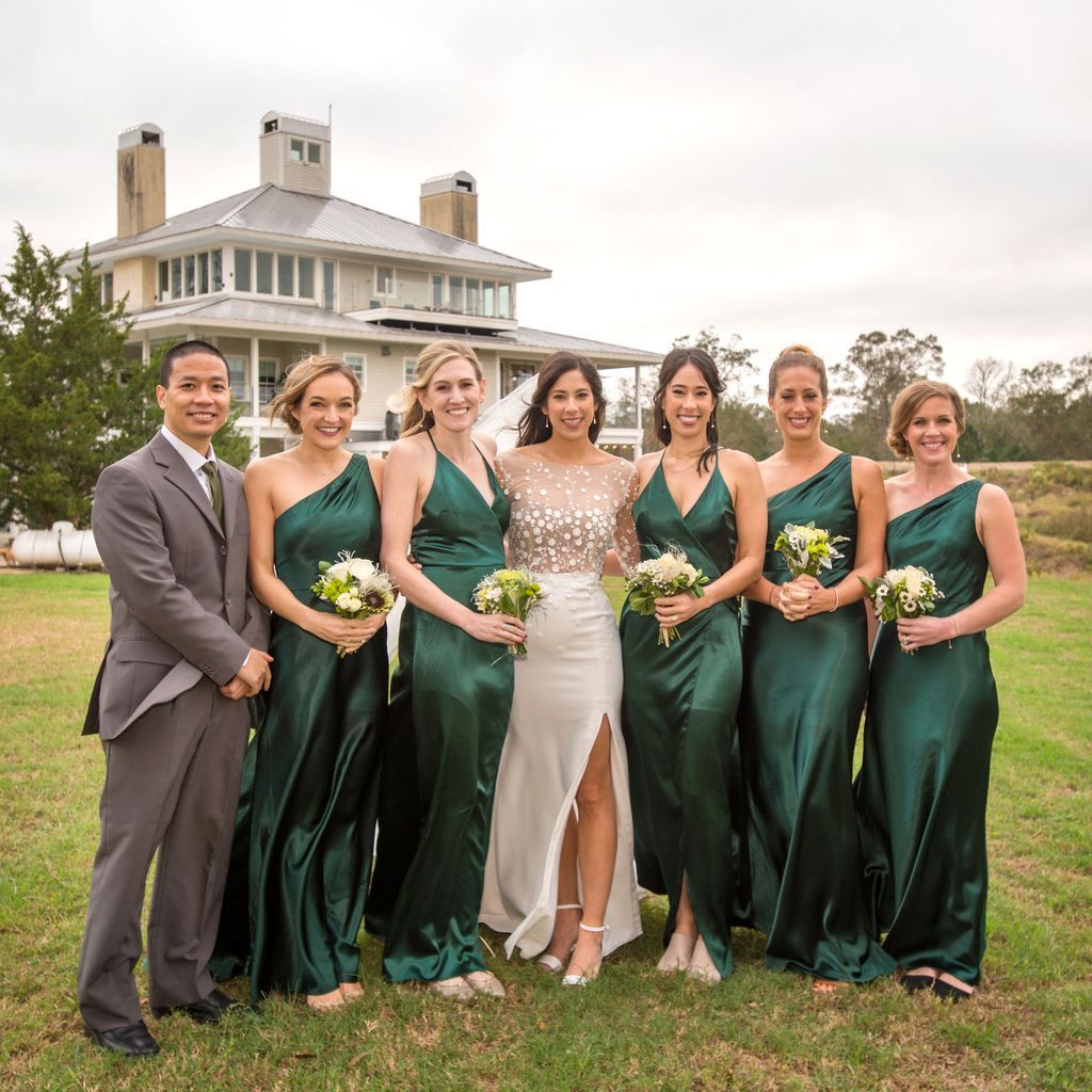 A bride and her bridesmaids are posing for a picture in front of a large house.