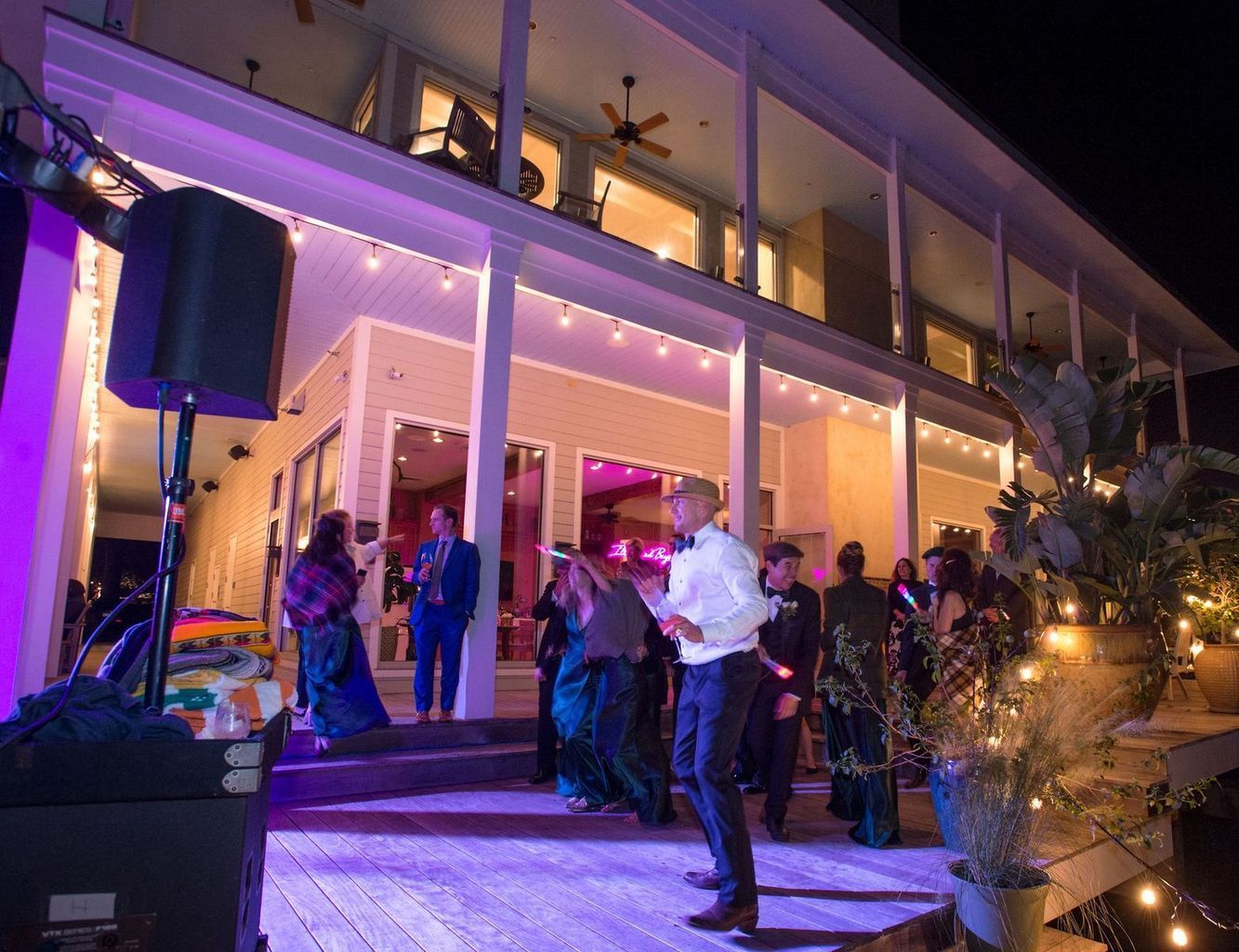 A group of people are dancing on a porch in front of a large building.