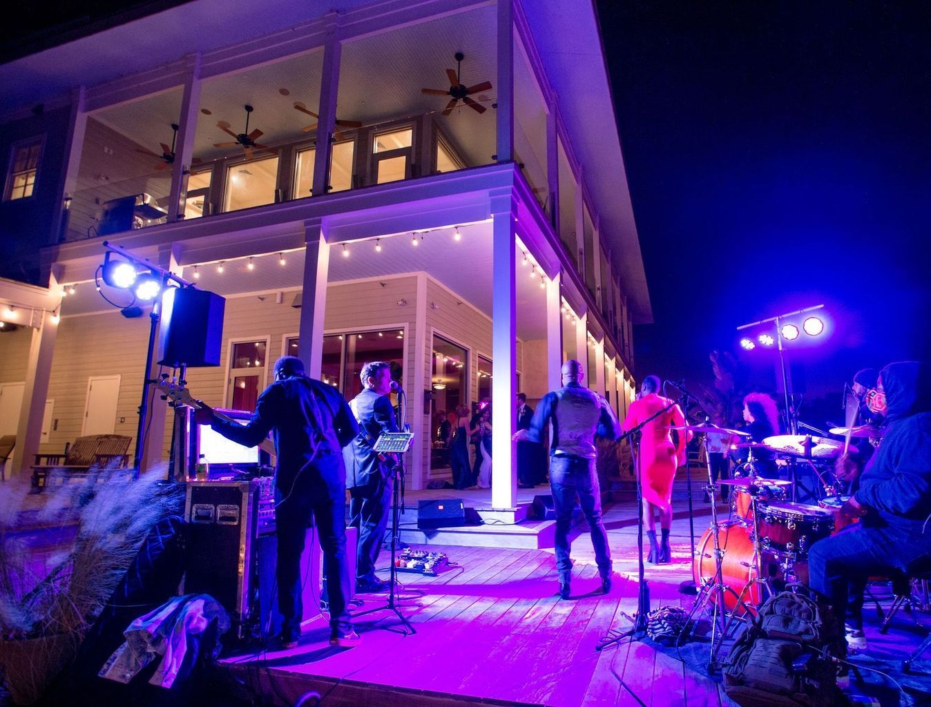 A group of people are playing instruments on a stage in front of a large building at night.