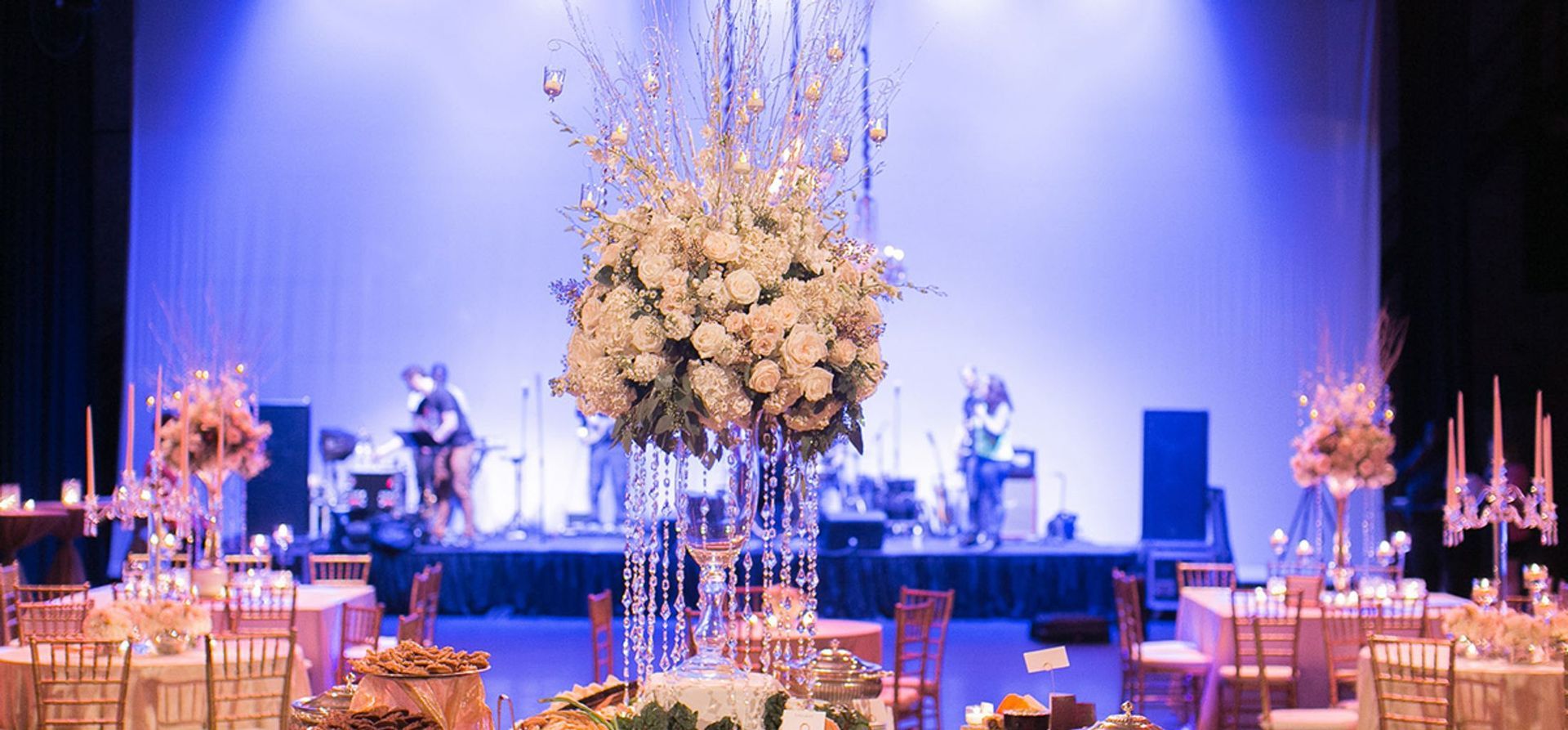 A large stage with tables and chairs set up for a wedding reception.