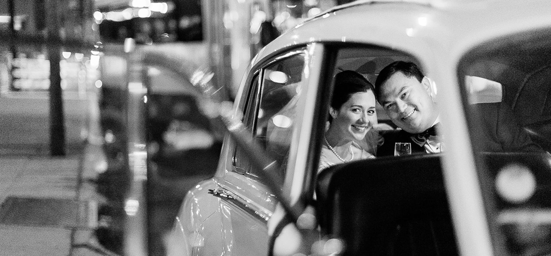 A black and white photo of a bride and groom in a car.